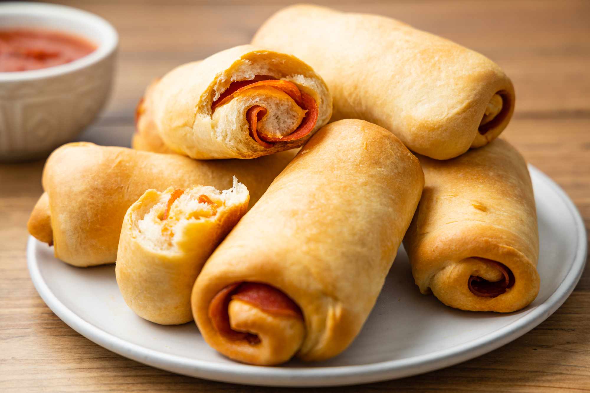 Pepperoni Rolls on a Plate with Bowl of Marinara in Background