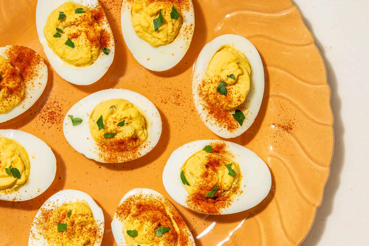 Overhead shot of a plate of deviled eggs on a bright orange plate